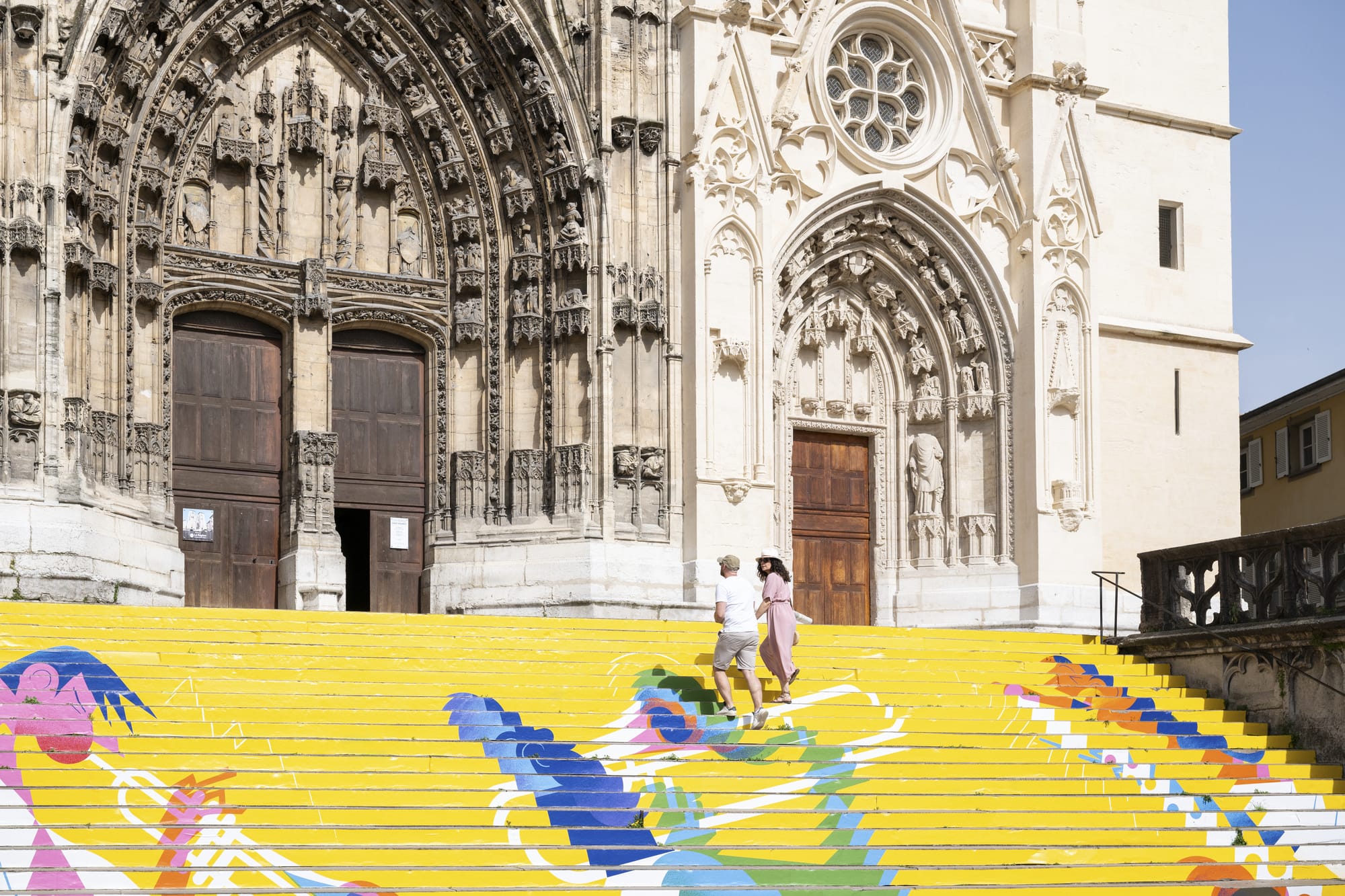 couple monte des escaliers colorés vers une cathédrale